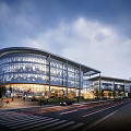 Modern Commercial Complex With Glass Facade Illuminated At Night And Urban Pedestrians