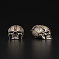Two Decorative Skulls With Gold Silver Accents Intricate Patterns On Black Reflective Background