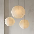 Three Spherical Beige Paper Pendant Lights with Warm Glow against Grey Wall Background