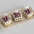 Three Square Tiramisu Cakes With White Cream Puffs Pink Pearls On Light Beige Rectangular Tray