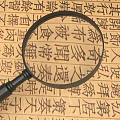 Magnifying Glass Examining Ancient Book Page With Traditional Chinese Text Characters
