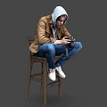 A Man Sitting On Wooden Chair Holding Camera Wearing Brown Jacket Gray Hoodie Blue Jeans
