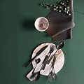 Tableware Set Featuring Wooden Tray Black Cutlery Marble Bowl And Green Leaves On Green Background