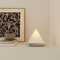 Modern Triangle Table Lamp on White Shelf with Stacked Books and Framed Decorative Painting
