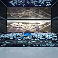 Modern Exhibition Space With Large Screen Showing Aerial Architectural View And Surrounding Architectural Models 3d model
