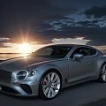 Silver Bentley Luxury Sports Car Parked At Seaside During Sunset With Cloudy Sky