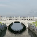 Classic Stone Arch Bridge Featuring Stone Railings Over Calm Water And Grass Banks