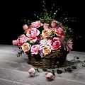 Pink and Beige Flower Arrangement in Wicker Basket with Green Leaves on Wooden Table