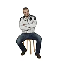 A Man Sitting on Wooden Stool with Crossed Arms in White Jacket and Blue Jeans