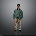 Man in Green Jacket and Beige Pants Standing with Headphones on Gray Background