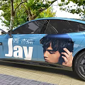 Blue Car With Jay Chou Image And JAY Text In Outdoor Setting With Trees