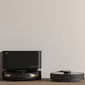 Black Smart Machine with Robotic Vacuum Cleaner on Wooden Tabletop against Light-colored Wall