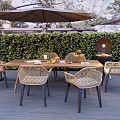 Rattan Outdoor Leisure Chairs In Garden Dining Area With Wooden Table Umbrella Grill And Greenery
