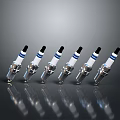 Six Spark Plugs With Silver Metal Black Tops Blue Stripes Neatly Arranged With Reflections