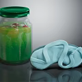 Glass Jar With Green Lid And Green Liquid Alongside Light Blue Slippers