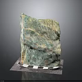 Large Natural Green and Yellow Textured Stone Decorative Piece on Checkered Mat with Dark Background