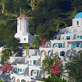 Santorini Style White Buildings With Blue Domes Palm Trees And Flowers On Hillside