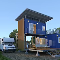 Blue Two Story Container House With Wooden Deck Outdoor Furniture And RV In Green Surroundings
