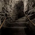 Dimly Lit Cavernous Basement Featuring Stone Stairs Rock Walls And Rope Railings