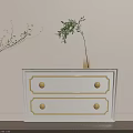 White Chest of Drawers With Gold Accents And Potted Plants Nearby