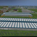 Aerial View of Industrial Factory Buildings With Blue Roof Panels Surrounded by Green Fields
