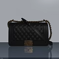 Black Quilted Handbag With Metal Chain Strap And Decorative Clasp On Light Background