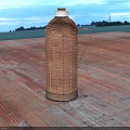 Classic Woven Rattan Thermos Flask on Wooden Platform with Green Field Background