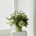 Green Vase With White Hydrangeas And Eucalyptus Leaves On White Table By White Blinds