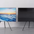 Two TVs Displaying Ocean Sunset Scene On Black Tripod Stands Against White Wall
