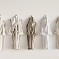 Soft Comfortable Bathrobes Hanging On White Wall In Various Neutral Colors