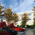 Modern Industrial Factory Building Featuring Autumn Trees Parking Lot And Parked Cars Under Blue Sky