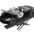Black Convertible Sports Car With Open Doors And Grey Seats On Display Platform
