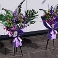 Elegant Floral Display With Purple Wrapped Bouquets On Black Tripods Against White Wall