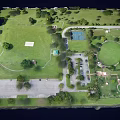 Aerial View of Park with Green Grass Trees Parking Lot and Basketball Court