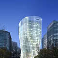 Modern Twisted Skyscraper With Glass Curtain Wall Against Blue Sky And Surrounding Buildings