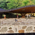 Curved Roof Building With Green Trees And People Gathering Outdoor Stone Wall Railings