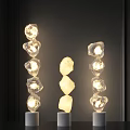 Three Modern Stacked Stone Like Floor Lamps Illuminated On Dark Background