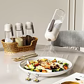 Kitchen Counter With Spice Containers In Basket Salad Being Sprinkled With Salt And Utensils
