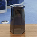 Modern Dark Glass Cup With Hexagonal Design On Wooden Table And Blue Carpet
