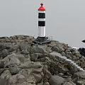 Red And Black White Lighthouse Tower Standing On Rocky Coastal Area