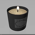 Lit Candle In Black Container With White Wax And Decorative Label
