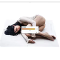 Woman Curled Up On White Mat Wearing Light Knit Sweater With Long Black Hair Resting