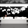 White Display Table With Items And Flying Papers Under Overhead Lighting On Black Background