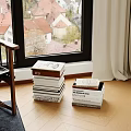 Stacked Books In Cozy Window Reading Corner With Natural Light And Scenic View