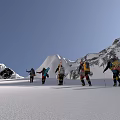Group of People Trekking in Snowy Mountain Range With Trekking Poles And Backpacks