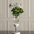 Clear Glass Vase With White Daisies Green Leaves On White Pedestal Against Light Paneled Wall