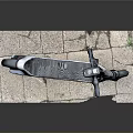 Silver Electric Scooter With Black Handlebar HEX Logo And Wheels On Stone Slab Surface