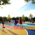 Outdoor Basketball Court With Colorful Surface People Playing Basketball Under Sunny Sky Surrounded by Trees