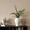 White Vase With Green Foliage On Black Bookshelf Featuring Monkey Sculpture Books And Metal Decor