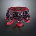 Round Dining Table With Red Blue Patterned Tablecloth And Pink Fringed Edges Wooden Legs
